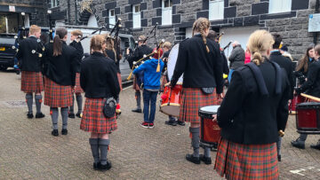 Oban High School pipe band lining up on the street next to Oban Disillery