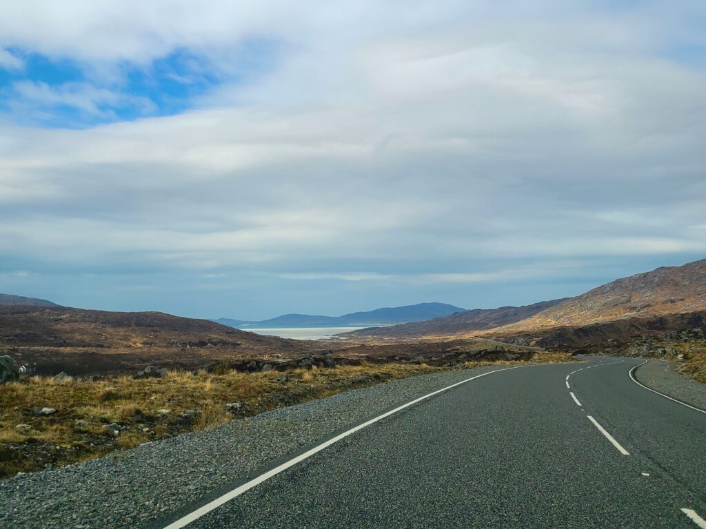 An empty highway between mountains to the sea in Scotland on a cloudy day.