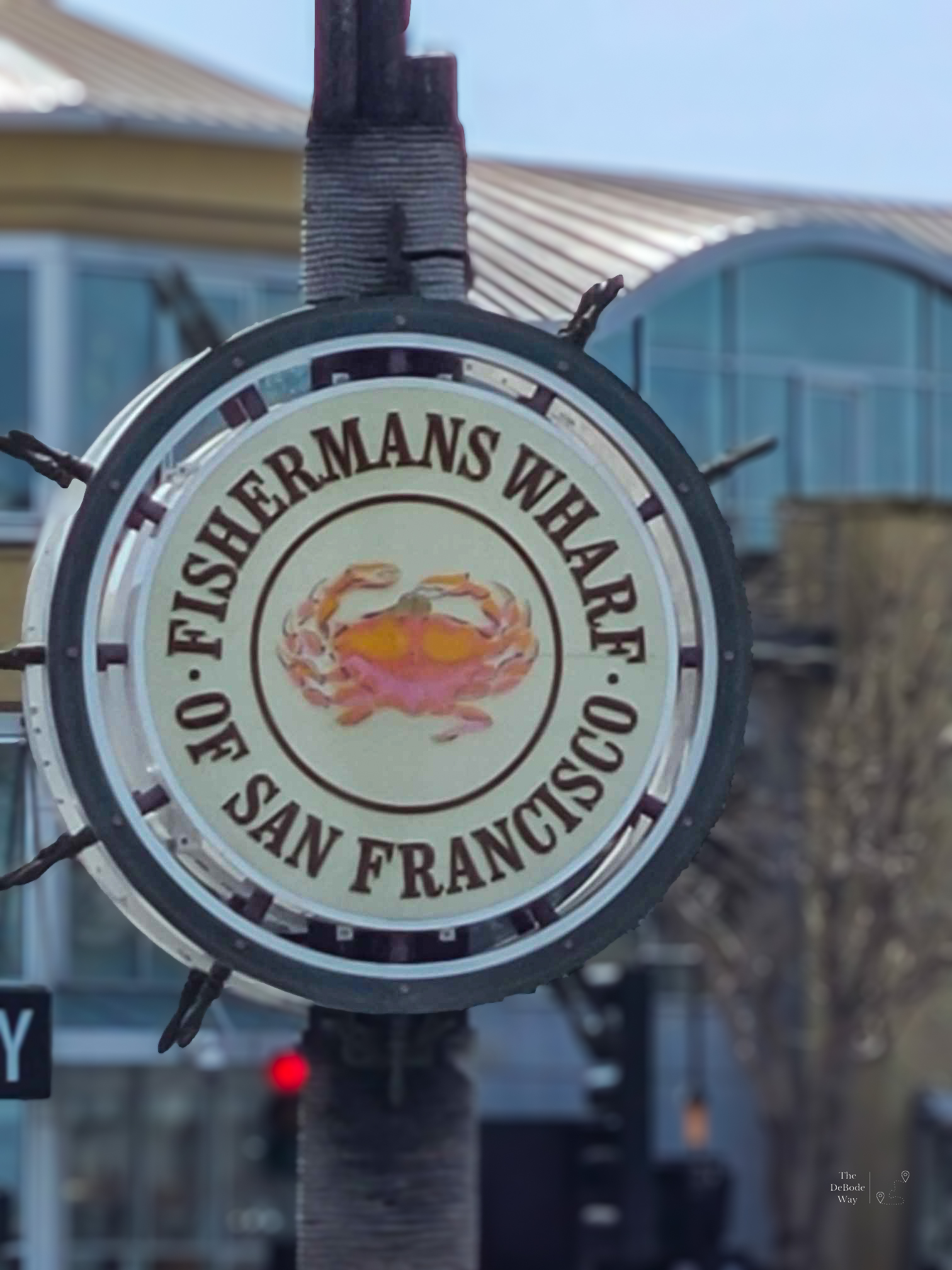 Ship's wheel shaped sign for Fisherman's Wharf in San Francisco with a crab at the center.
