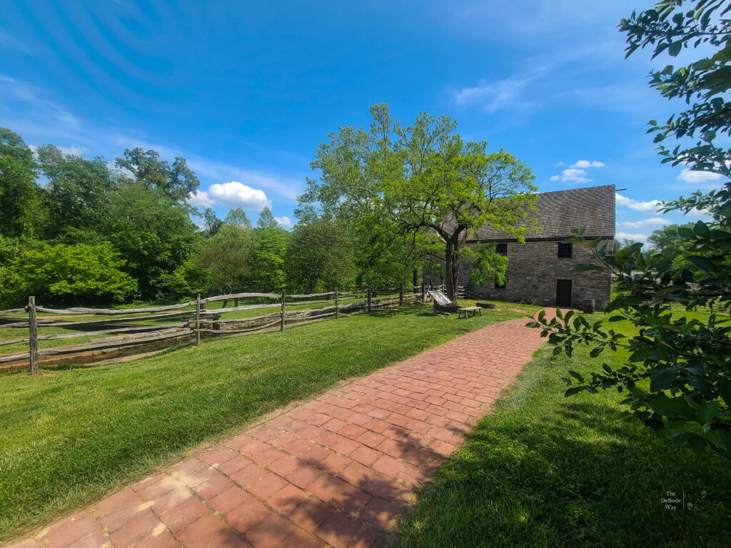 The brick path and split-rail fence lead to the stone building, where George Washington's grain mill is located.