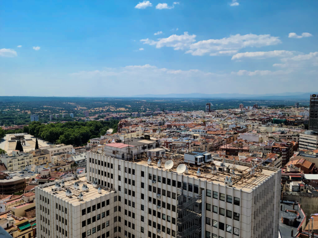 Looking west across the Madrid rooftops to the green spaces and mountains beyond.