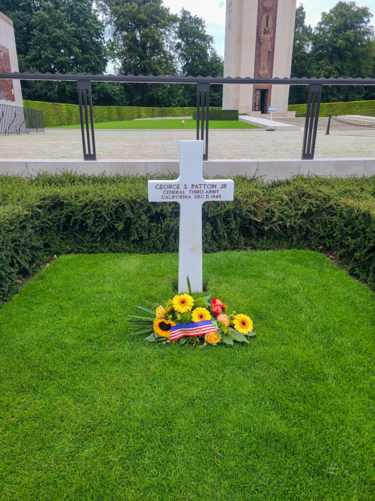 General Patton's white cross with flowers at the base at his grave at the Luxembourg American Cemetery