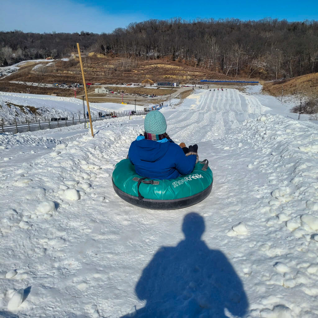 Tasha is sitting in a snow tube at the  top of the run